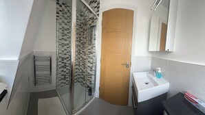 Ein Badezimmer mit Dusche, Waschbecken und Spiegel.
