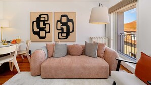 A modern living room with a sofa, a dining table, and two abstract paintings. - Modern Flat in Central Lisbon (Lisbon)