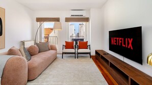 A modern living room with a sofa, chairs, a TV, and a view through a window. - Modern Flat in Central Lisbon (Lisbon)