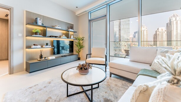 Una sala de estar moderna con un sofá, una mesa de centro redonda y un mueble empotrado para entretenimiento.