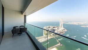 En balkon med udsigt over et kystnært bybillede, herunder et stort pariserhjul og en bro.