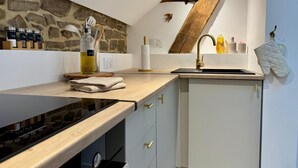 Une cuisine moderne avec un pare-feu en pierre, un plan de travail en bois et un four encastré.