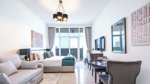 Ein modernes Hotelzimmer mit Bett, Sofa, Esstisch und Fernseher.