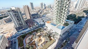 Ein hoch aufragendes Gebäude mit modernem Design, umgeben von anderen hohen Gebäuden und einer belebten Straße.