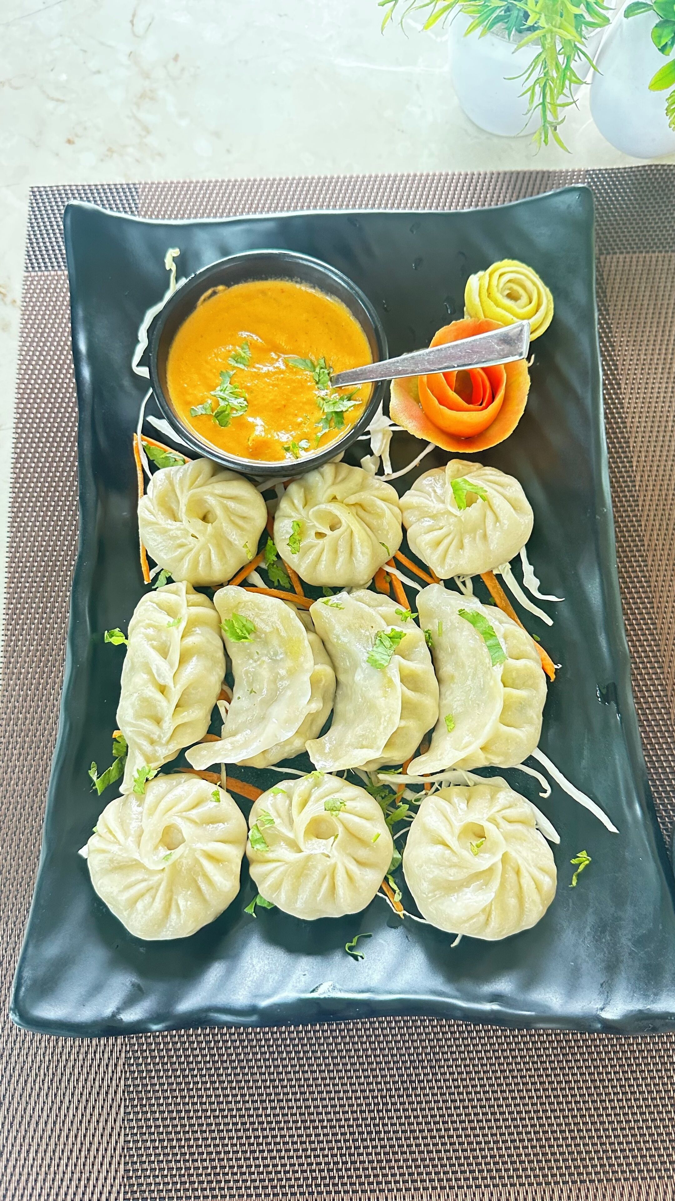A rectangular plate with dumplings, a bowl of soup, and a decorative flower.