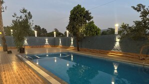 Piscina interna com deck de madeira e um muro baixo.
