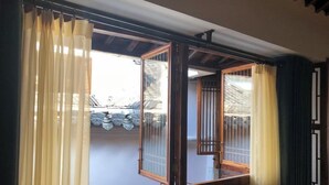 A traditional Japanese room with tatami flooring, a sliding shoji screen door, and a view of a traditional Japanese garden. - zz's hotel (Haikou)