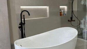 A modern bathroom with a freestanding bathtub, a glass shower enclosure, and a minimalist design. - zz's hotel (Haikou)