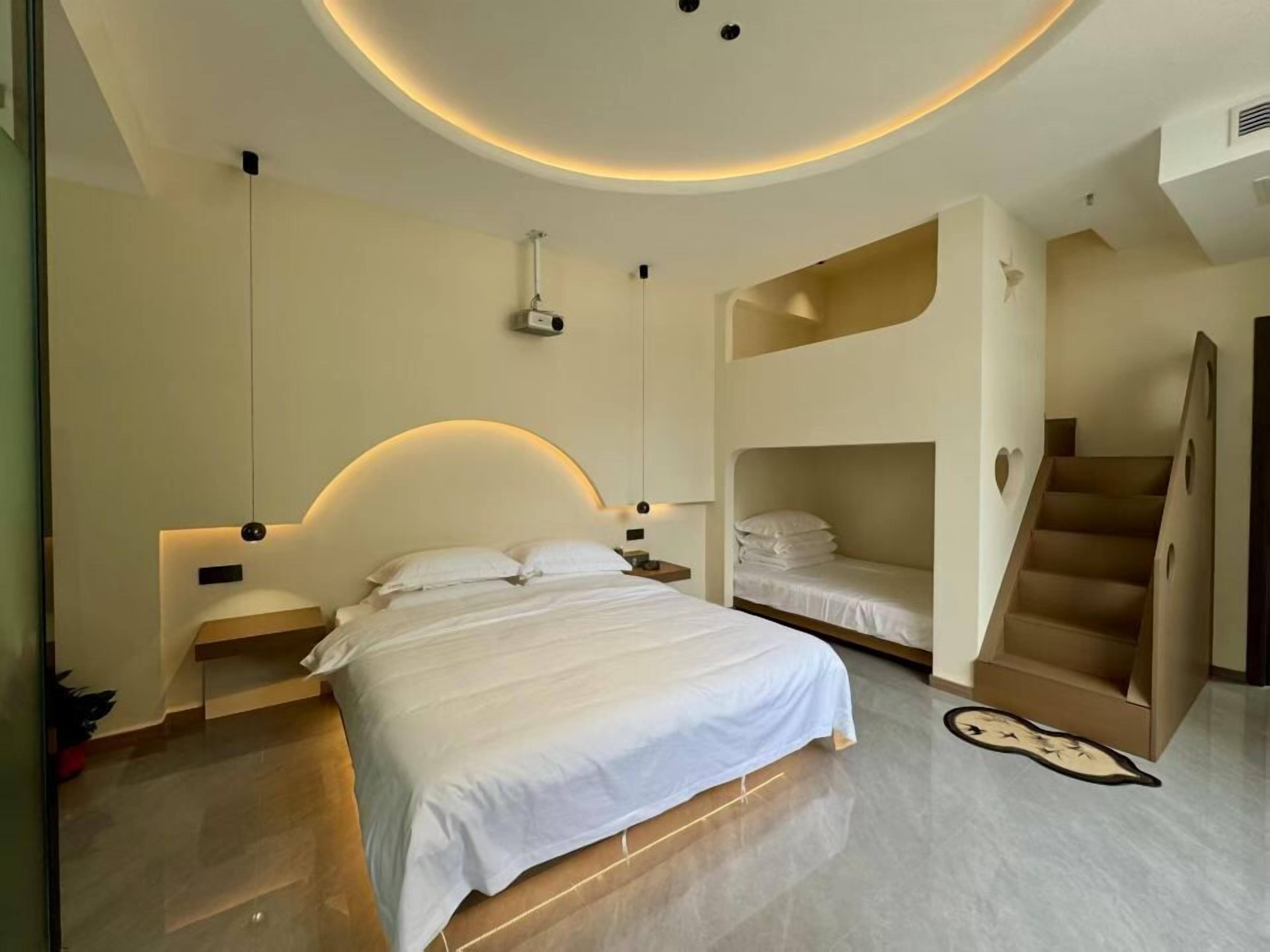 A modern bedroom with a large bed, a bunk bed, a staircase, and a unique clock on the floor.