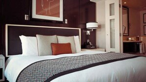 A hotel room with a large bed, a headboard, a bedside table with a lamp, and a framed picture on the wall. - zz's hotel (Haikou)