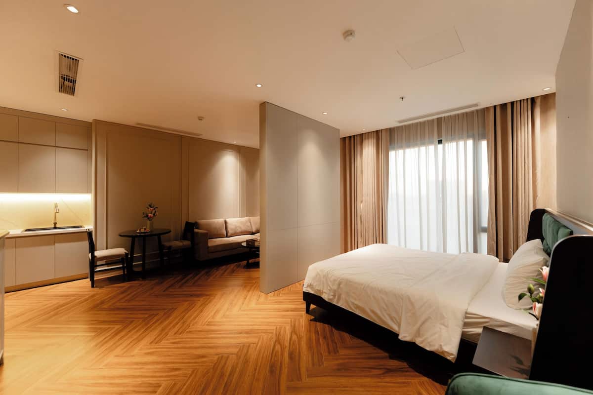 Una habitación de hotel moderna con una cama grande, un sofá, una mesita y un escritorio.