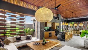 A modern living area with a sofa, coffee table, and dining area. - 12 Bedroom Myosotis VVV (Ubud)