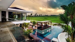 A modern house with a glass balcony overlooking a lush green field. - 12 Bedroom Myosotis VVV (Ubud)