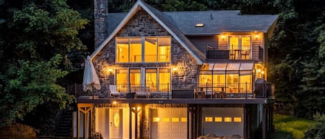 A two-story house with a stone facade, multiple windows, and a covered porch with outdoor seating.