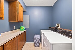 A laundry room with wooden cabinets, a washing machine, and a dryer. - Riverfront Cabin Getaway with Fire Pit! (Harpers Ferry)
