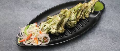A black plate with grilled vegetables and a side salad.
