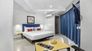 Une chambre d’hôtel avec un lit, une table avec des collations, une télévision et une fenêtre avec des rideaux.