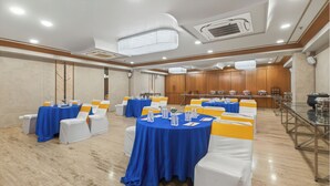 Une salle de conférence avec des tables rondes, des chaises blanches et des nappes bleues.