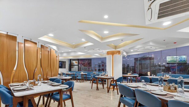 Un restaurant moderne avec des cloisons en bois, des chaises bleues et des tables blanches.