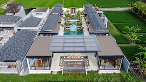 Un moderno resort con una piscina central, varias habitaciones para huéspedes y un exuberante paisaje verde.