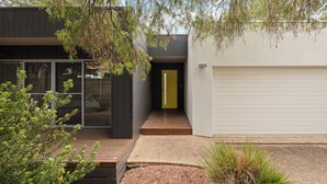 Une maison moderne avec une terrasse en bois, un garage et une porte jaune.