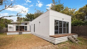 Une maison moderne de plain-pied, dotée d’un toit plat, de grandes fenêtres et d’une terrasse en bois.