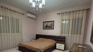A bedroom with a bed, a nightstand, a dresser, a chandelier, and a framed picture on the wall. - Nice an calm Apartment in Tirana City (Tiranë)