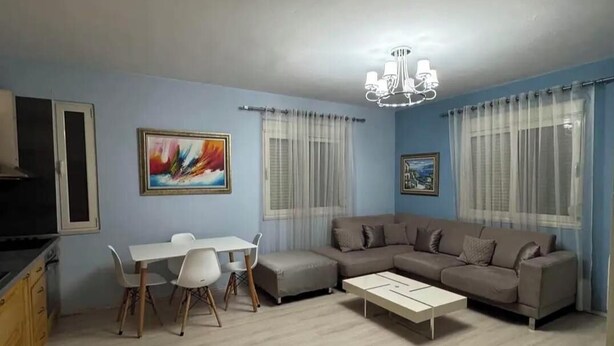 A living room with a sofa, a dining table with chairs, a TV, and a chandelier. - Nice an calm Apartment in Tirana City (Tiranë)