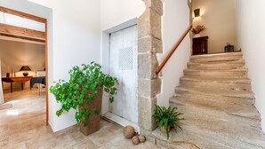 Un escalier avec des marches en pierre, une rampe en bois et une porte blanche ornée d’un panneau texturé.