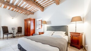 Une chambre à coucher comprenant un lit, deux chaises, une table, une armoire et une lampe.