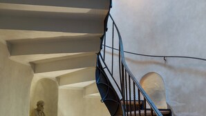 A spiral staircase with a statue on the left and a lit-up wall on the right. - Boutique hotel Soukeníkův dům (Kutna Hora)