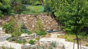 A stone patio with a round table and chairs, surrounded by a stone wall and a metal fence. - Boutique hotel Soukeníkův dům (Kutna Hora)