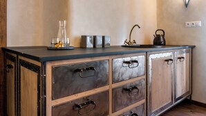 A kitchen with a wooden cabinet, a black countertop, and a kettle. - Boutique hotel Soukeníkův dům (Kutna Hora)
