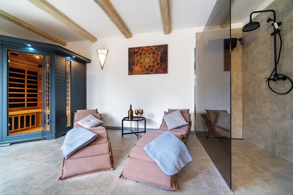 A spa room with two massage beds, a wall-mounted shower, and a wooden ceiling.