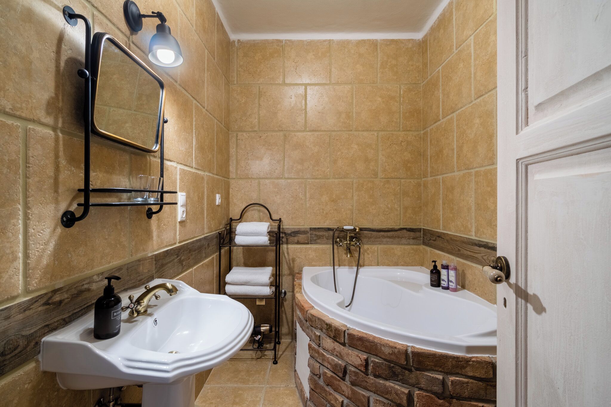 Un baño con lavamanos, espejo, toallero y bañera.