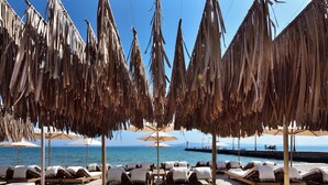 A beachside lounge area with wooden lounge chairs and umbrellas, overlooking the sea. - Adriana Beach (Pefkochori)