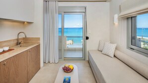 A modern room with a kitchen, a balcony with a view of the sea, and a seating area with a bowl of fruit. - Adriana Beach (Pefkochori)
