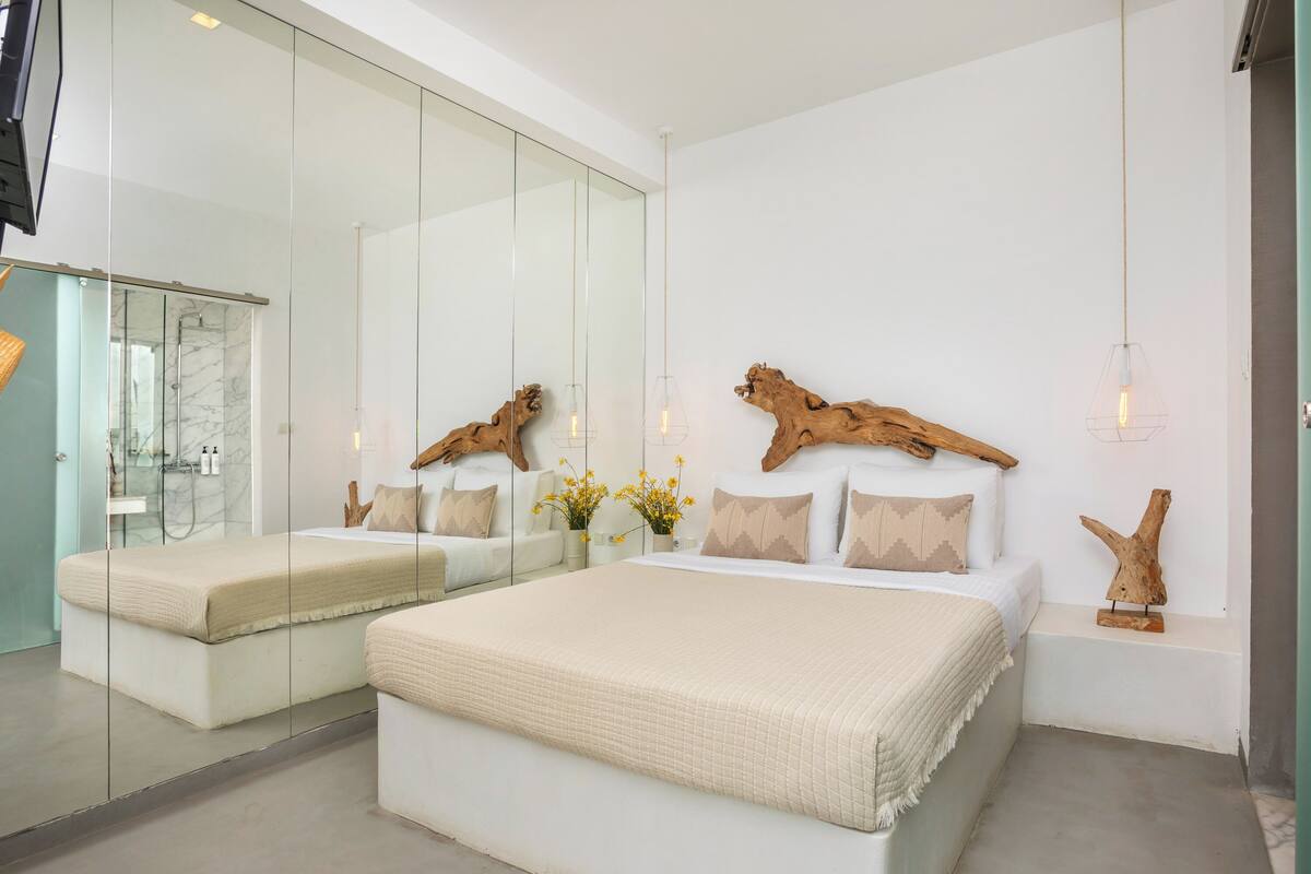 A modern bedroom with a large bed, a glass shower enclosure, and a wooden headboard.