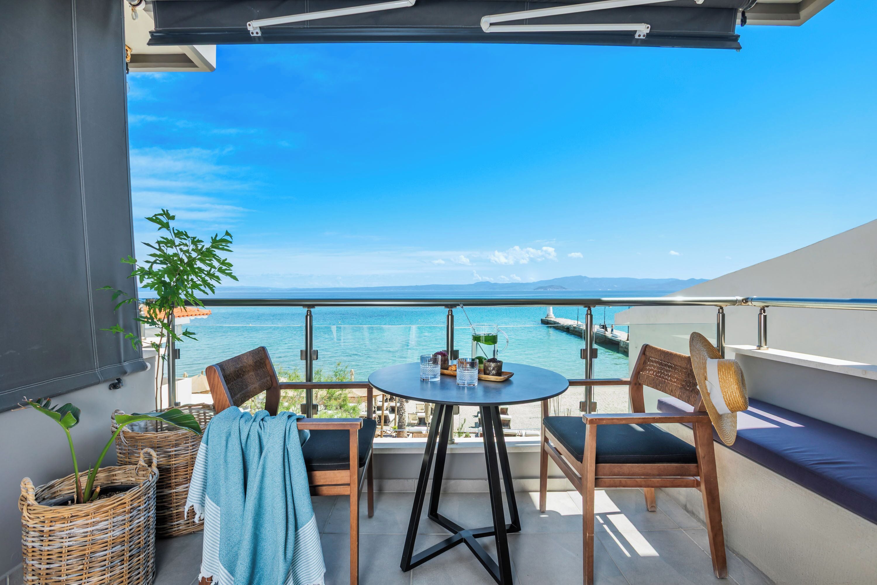 A balcony with a table and chairs, overlooking a body of water and distant land.