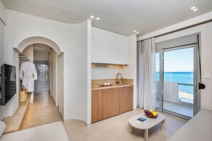 A modern hotel room with a kitchenette, a dining area, and a balcony with a view of the sea. - Adriana Beach (Pefkochori)