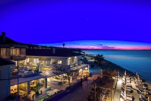 A beachfront hotel with outdoor seating, a pool, and a view of the ocean. - Adriana Beach (Pefkochori)