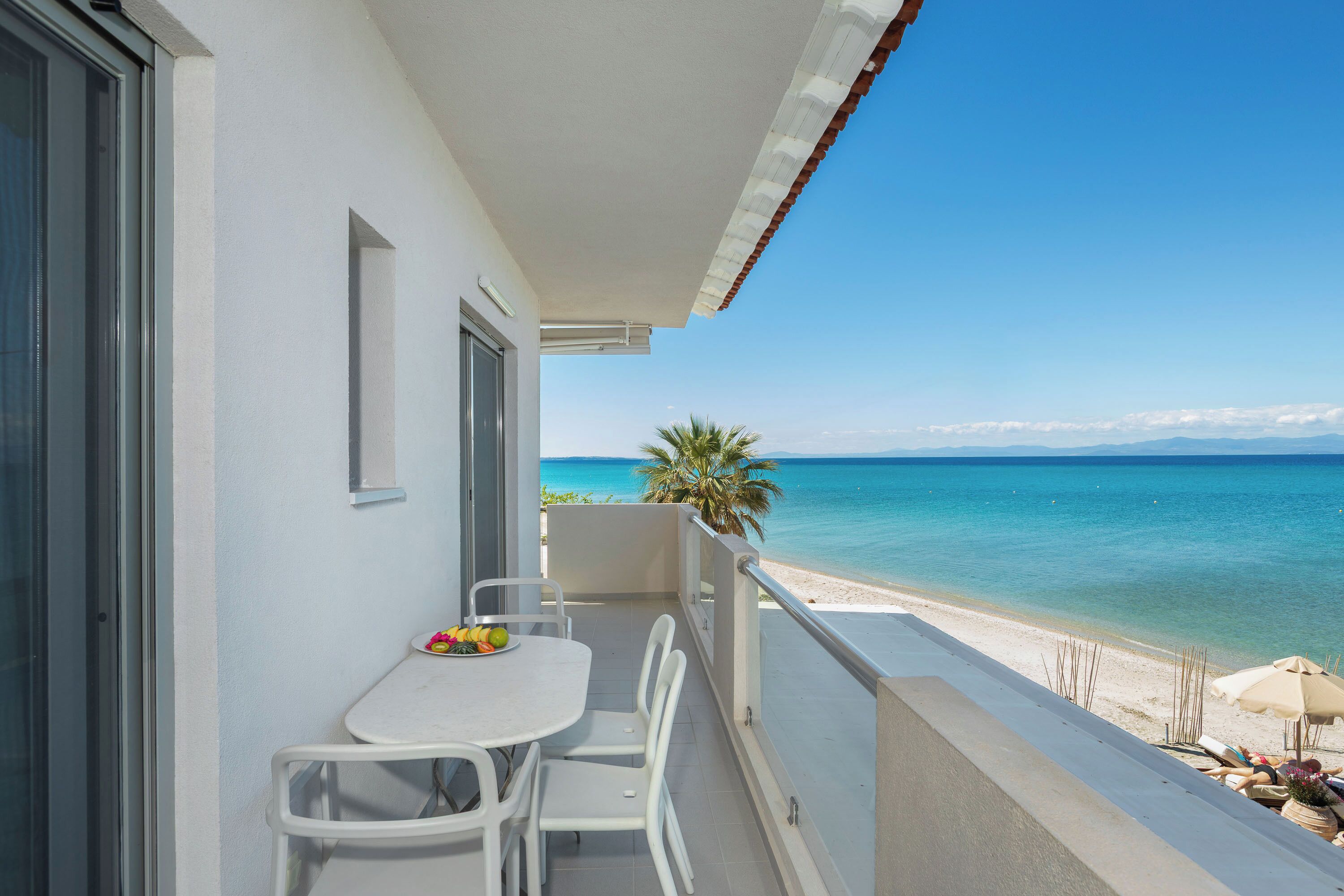 A balcony with a table and chairs overlooking a beach.