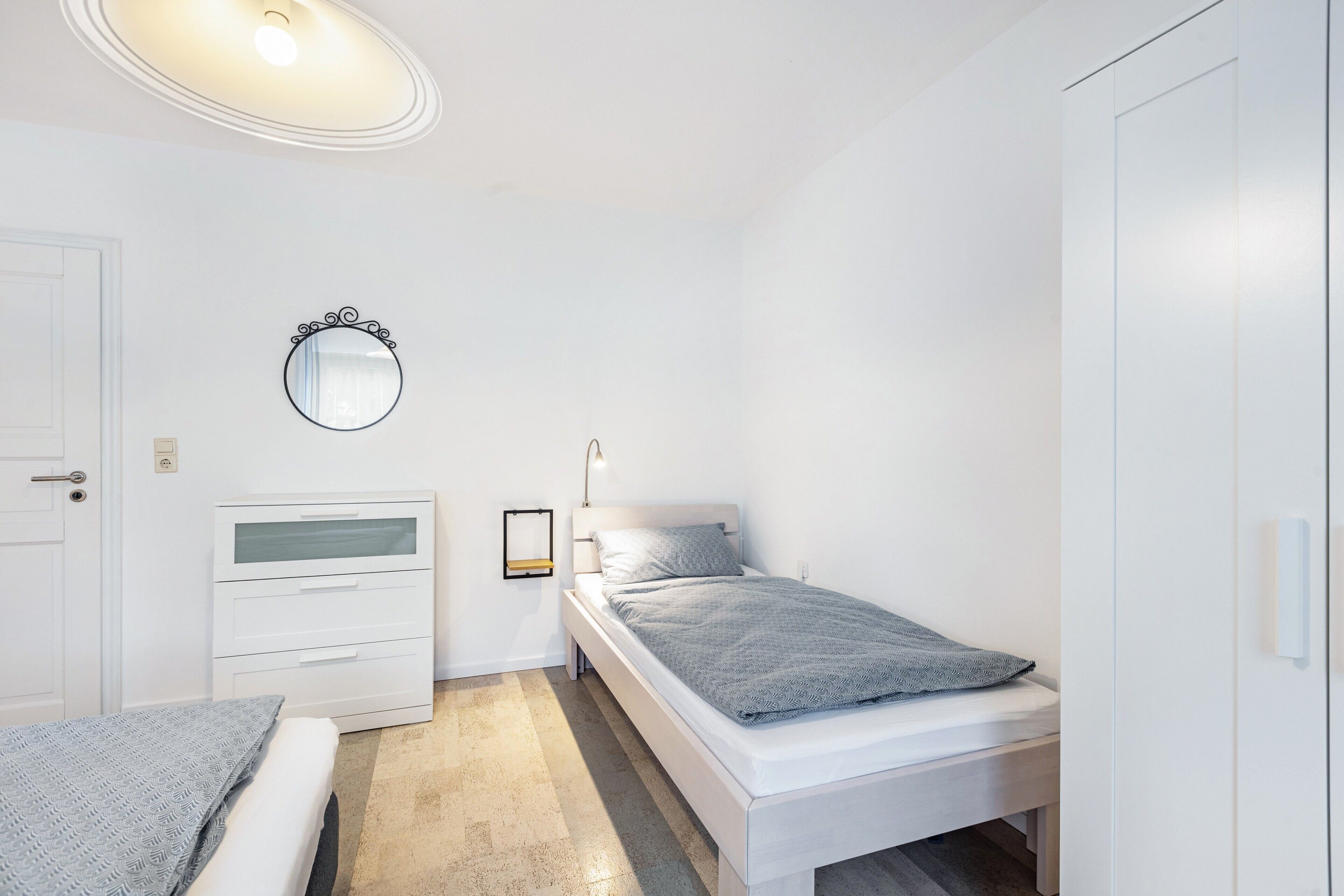 A bedroom with a bed, a bedside table, a mirror, and a wardrobe.