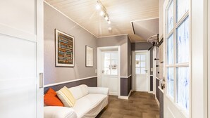 A hallway with a white sofa, a framed word cloud on the wall, and a door leading to another room.