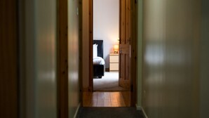 A narrow hallway leading to a bedroom with a bed, bedside table, and lamp. - Westwood in Oban Town Centre (Argyll and Bute Council)