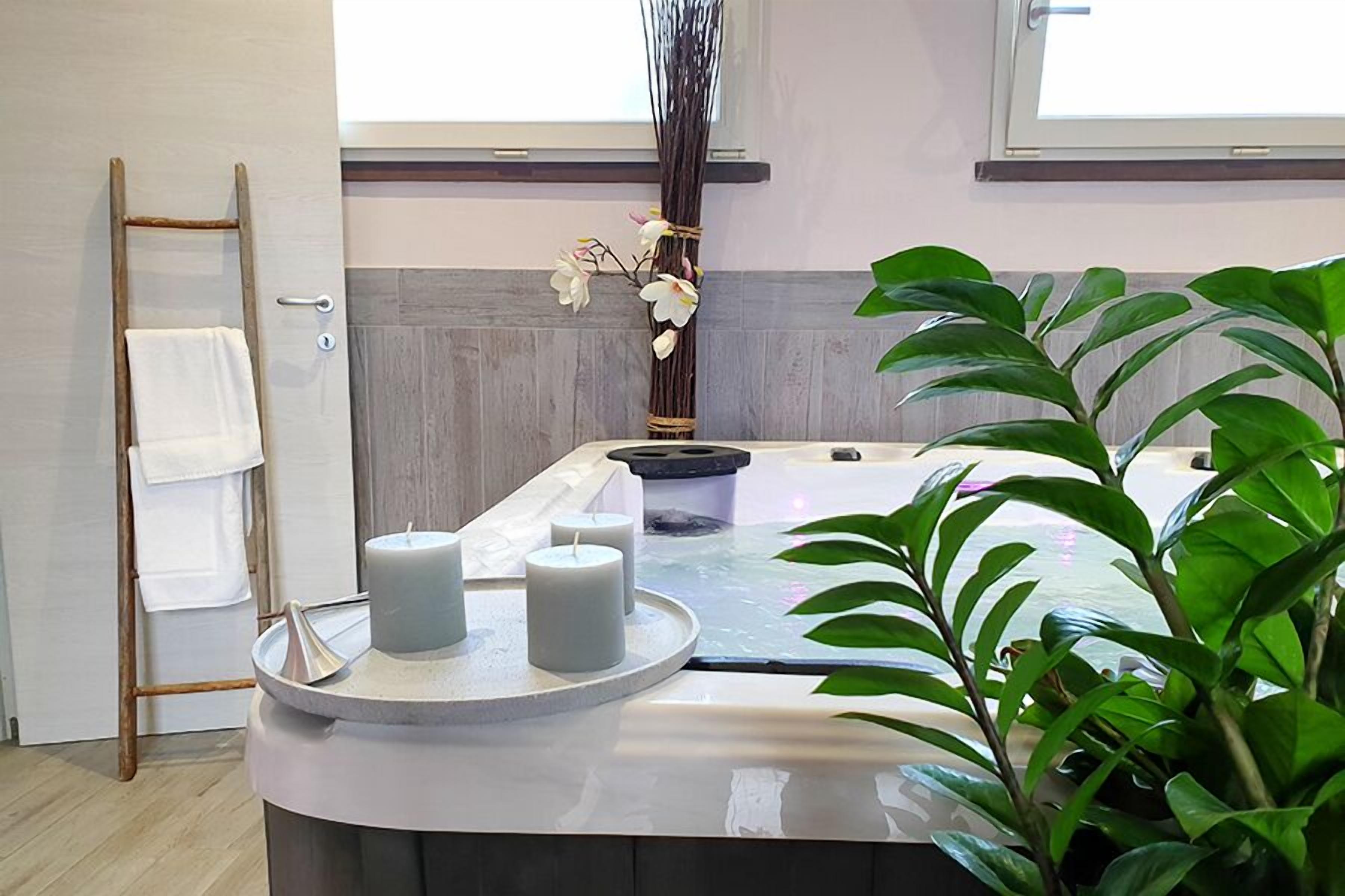 A spa area with a massage table, candles, a towel rack, and a potted plant.