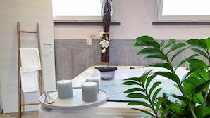 Un espace spa comprenant une table de massage, des bougies, un porte-serviettes et une plante en pot.