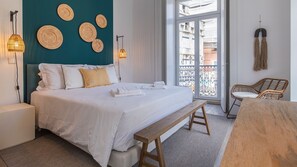 A bedroom with a bed, bedside tables, a bench, and a view of the outside balcony. - Ando Living - Abrantes Flats - 14 (Lisbon)