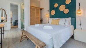 Ein Schlafzimmer mit einem großen Bett, einer hölzernen Bank, einem Schreibtisch und einem Spiegel.