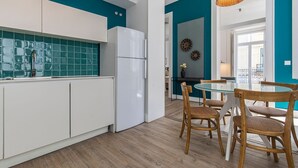 Une cuisine moderne avec des meubles blancs, un réfrigérateur blanc et des carreaux de crédence de couleur turquoise.